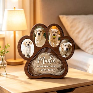 Könnte beinhalten: Ein pfotenförmiger Holzbilderrahmen mit dunkelbrauner Holzmaserung. Er verfügt über vier ovale Fotofächer mit Bildern eines gelben Labradors und einen mittleren Bereich mit dem Text Madie FOREVER LOVED 2014-2026.