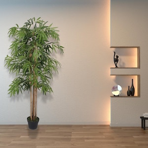 Peut inclure: Un grand plant de bambou artificiel dans un pot noir, debout sur un sol en bois devant un mur blanc avec une étagère intégrée. L'étagère a un miroir rond, deux vases noirs et une sculpture décorative noire.