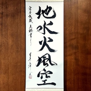 May include: A white scroll with black calligraphy in Chinese characters. The characters read "火水風空" which translates to "Fire, Water, Wind, Space".