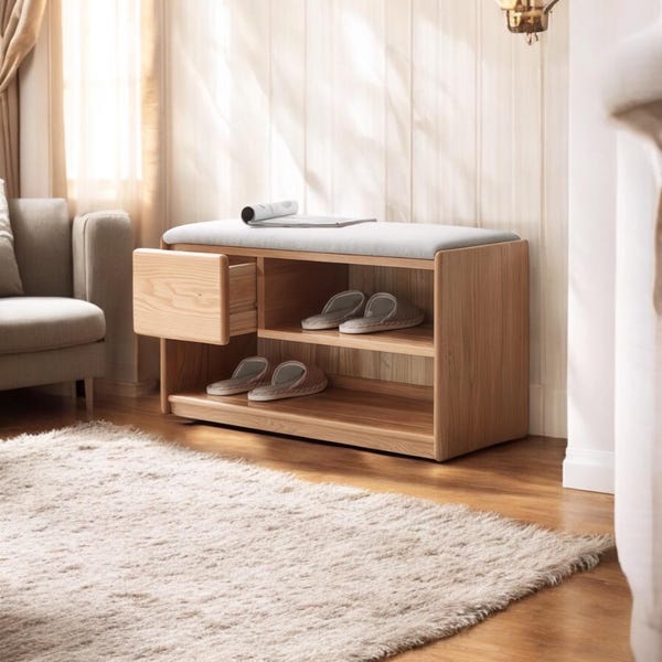 Puede incluir: Un banco de almacenamiento de zapatos de madera con una parte superior acolchada, dos estantes y un cajón. El banco está hecho de madera clara y tiene un acabado natural. Los estantes están vacíos y el cajón está abierto.