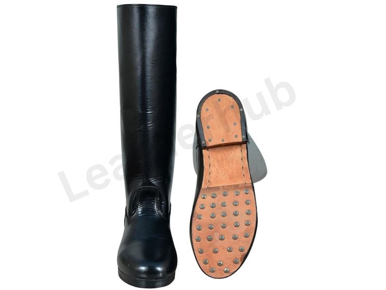 May include: Black leather riding boot with a matching sole. The sole is studded with metal cleats. The boot is tall, reaching the knee. The second boot is shown with the sole facing up.