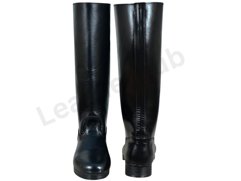 May include: A pair of tall, black leather riding boots. The boots have a smooth, glossy finish and a classic design, with a rounded toe and a low heel. The boots are displayed against a white background.