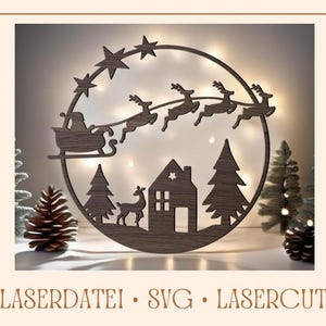Op de afbeelding: Een houten lasergesneden ornament met Sinterklaas die in een slee vliegt die door rendieren wordt getrokken, een huis en een kerstboom. Het ornament heeft een ronde vorm met een houtnerfstructuur.