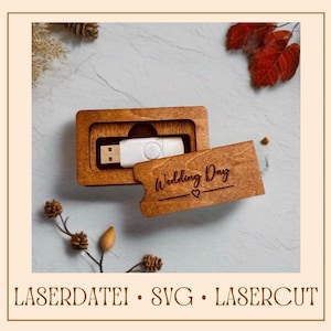 以下が含まれることがあります： 「Wedding Day」と小さなハートが刻まれた、スライド式の蓋が付いた木製の箱。箱が開いており、中には白いUSBドライブが入っています。