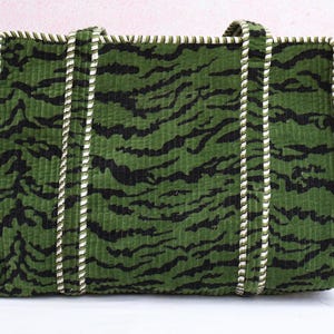 May include: Green corduroy tote bag with black tiger stripe pattern. The bag has white and green rope handles and trim. A stylish and functional accessory for carrying essentials.