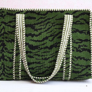 May include: Green tote bag with a black tiger stripe pattern. The bag has white and green striped handles and trim. The bag is rectangular and appears to be made of a corduroy-like material.