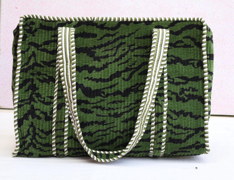 May include: Green tote bag with a black tiger stripe pattern. The bag has white and green striped handles and trim. The bag is rectangular and appears to be made of a corduroy-like material.