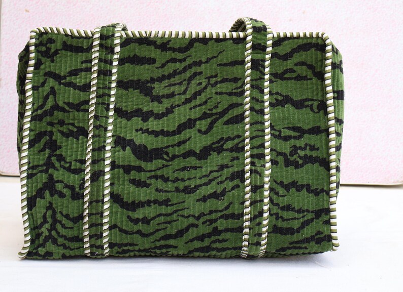 May include: Green corduroy tote bag with black tiger stripe pattern. The bag has white and green rope handles and trim. A stylish and functional accessory for carrying essentials.