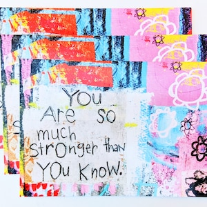 May include: A set of four colorful cards with a message that reads "You are so much stronger than you know." The cards have a collage-style design with bright colors, abstract shapes, and flowers.