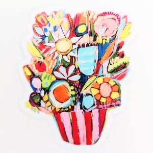 May include: A colorful bouquet of flowers in a pink and red striped pot. The flowers are painted in a variety of bright colors, including yellow, orange, red, blue, and green.