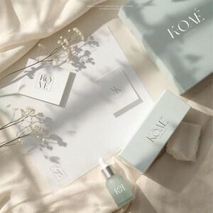 Aesthetic mockup on beige, gray, and soft aqua tones featuring skincare bottles, boxes, and envelopes styled with logos from the kit. Text clarifies ‘Mockups are for inspiration only, not included. For personal use only.’ Demonstrates potential brand applications and quiet luxury product presentation in a realistic photo style.