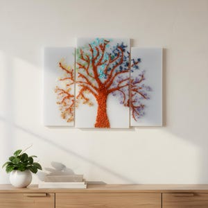 Op de afbeelding: Een driedelig kunstwerk aan de muur met een boomontwerp. De boomstam en takken zijn rood-oranje, met kleurrijke edelstenen die de bladeren vormen. De edelstenen omvatten tinten geel, blauw en paars.