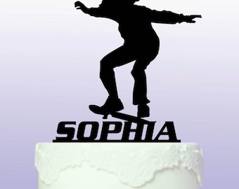 May include: Black silhouette of a person skateboarding with the name "Sophia" written below. This is a cake topper.