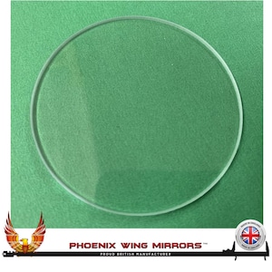 May include: A clear round glass replacement mirror for a car. The mirror is on a green background.