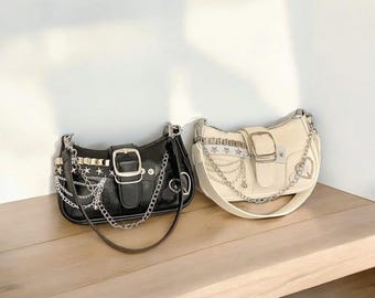 May include: Two chain strap handbags, one black and one white, with silver hardware and star accents. Both bags have a buckle closure and a chain strap.