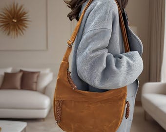 May include: A brown suede shoulder bag with a long strap and a braided detail. The bag has a flap closure and a small pocket on the front.