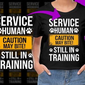 Puede incluir: Camiseta negra con texto blanco y huellas de patas. La camiseta dice "SERVICE HUMAN" encima de un letrero amarillo que dice "CAUTION MAY BITE!" y "STILL IN TRAINING" debajo. Un diseño divertido para los amantes de los perros.