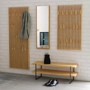 Op de afbeelding: Een moderne entree set met een volledige spiegel, twee houten kapstokken en een tweelaagse bank. De kapstokken hebben verticale houten latten met haken. Een grijze jas hangt aan één rek. Zwarte schoenen en een zwarte tas staan bij de bank.