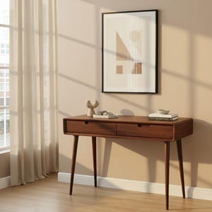 May include: A rectangular wooden desk with two drawers and four tapered legs. On the desk surface sits a small beige abstract sculpture, a pair of glasses on a white book, and a stack of two books with a small bowl on top, all in a room.