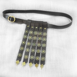 May include: A brown leather belt with a metal buckle and a series of hanging leather straps with decorative metal circles.