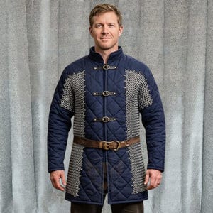 Peut inclure: Veste matelassée bleu marine avec des détails en cotte de mailles sur les épaules et les côtés. Elle comporte trois sangles en cuir avec boucles sur le devant et une ceinture en cuir marron. Vêtement pour reconstitution historique ou costume.