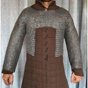 May include: A brown quilted tunic with a chainmail collar and sleeves. The tunic has a laced front closure.