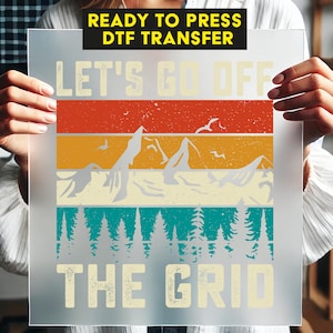 May include: Ready to press DTF transfer with a vintage-style graphic that says "Let's Go Off The Grid". The graphic features a mountain range, trees, and a sunset.