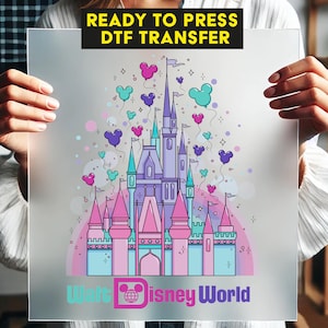 May include: A ready-to-press DTF transfer featuring a colorful illustration of a castle with balloons. The castle is in shades of pink, purple, and blue, with the words "Walt Disney World" at the bottom. The text "READY TO PRESS DTF TRANSFER" is at the top.