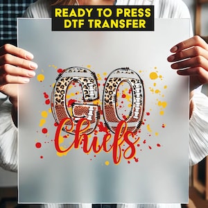 May include: A clear sheet with the words "READY TO PRESS DTF TRANSFER" in a black rectangle. The design features the words "GO Chiefs" in a football-themed design with leopard print accents and red and yellow splatter.