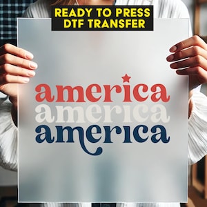 May include: A frosted sheet with the word "america" in red, white, and blue, with a star above the first word. The text "READY TO PRESS DTF TRANSFER" is in a black box at the top.