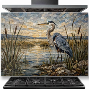 May include: A rectangular kitchen splashback panel featuring a mosaic-style illustration of a great blue heron standing on a rocky shore. The scene depicts a calm lake at sunset with tall cattails, soft blue and gold sky tones, and water reflections.