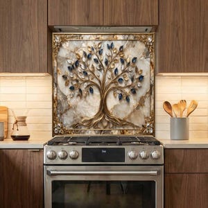 May include: A decorative kitchen backsplash featuring a golden tree design with blue and gold leaf accents. The tree is set against a marble-like background within a gold frame. The backsplash is installed above a stainless steel stove.