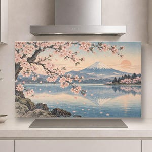 Puede incluir: Un panel protector de cocina rectangular que presenta una ilustración de paisaje impresa de una montaña nevada, un lago tranquilo y un gran cerezo con flores rosas en primer plano bajo un cielo de amanecer de color naranja pálido.