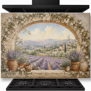 Puede incluir: Un mural rectangular para salpicadero de cocina compuesto por múltiples azulejos que muestra un paisaje pintado de campos de lavanda vistos a través de un arco de piedra. Incluye macetas de terracota con lavanda y flores blancas.