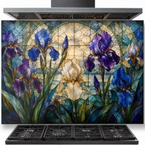 May include: A rectangular kitchen backsplash panel featuring a stained glass style print of purple, blue, and white iris flowers. The design includes green foliage and a circular arched background pattern, positioned behind a black four-burner gas stovetop.
