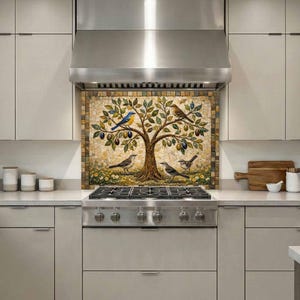 May include: A mosaic backsplash featuring a tree with birds and fruit. The tree has green leaves, brown branches, and is adorned with blue, yellow, and brown birds. The backsplash is installed above a stainless steel gas range in a modern kitchen.