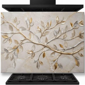 May include: A rectangular kitchen splashback panel featuring a beige marble-effect background with a raised, three-dimensional metal branch design. The branches are finished in alternating metallic gold and silver tones with leaf accents.
