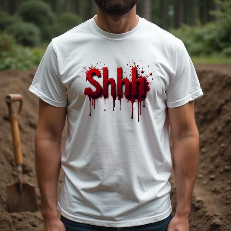 Pu&ograve; includere: T-shirt bianca con la scritta "Shhh" in rosso, con un design a gocce simile a sangue. La maglietta &egrave; a maniche corte e girocollo. Sullo sfondo, una pala e un cumulo di terra.