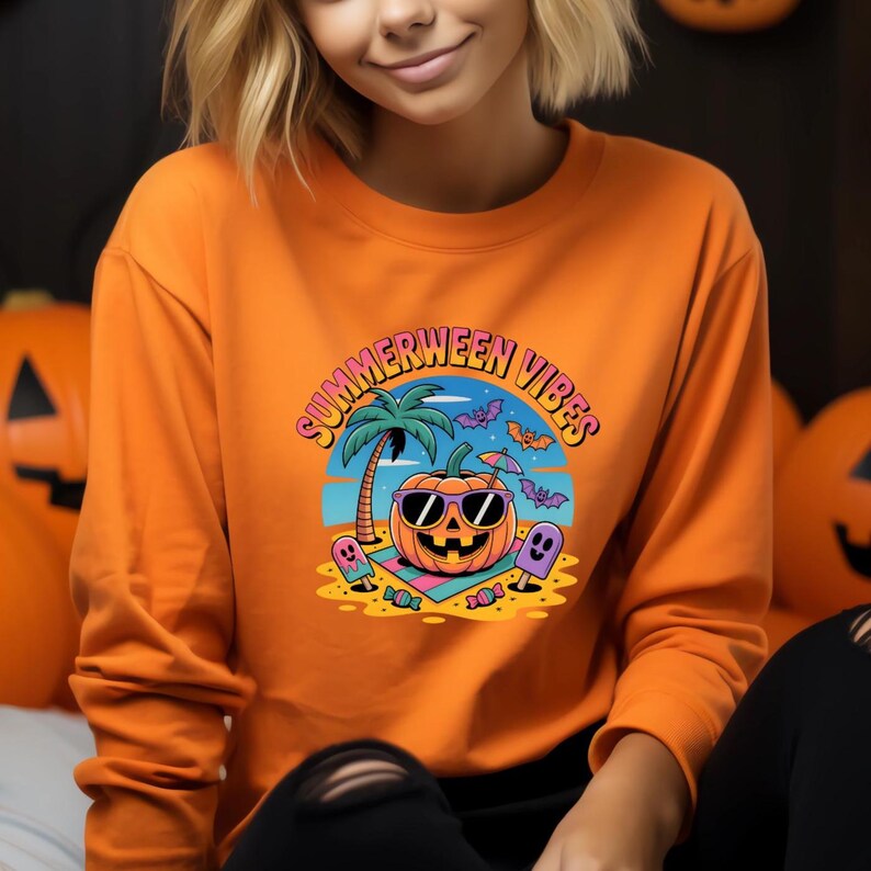 May include: Orange long-sleeve sweatshirt with a graphic that says "Summerween Vibes." The graphic features a pumpkin wearing sunglasses on a beach with a palm tree, bats, and ghosts. The sweatshirt is a solid orange color.