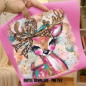 Puede incluir: Una descarga digital rosa con una ilustración de un ciervo. El ciervo tiene un lazo con estampado de leopardo, cuernos dorados y largas pestañas. El fondo tiene pinceladas coloridas y detalles dorados. El texto en la parte inferior dice "DESCARGA DIGITAL - ARCHIVO PNG."