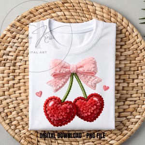 Può includere: T-shirt bianca con un fiocco rosa e due ciliegie rosse a forma di cuore con gambi verdi. Il design include piccoli cuori rosa e il testo "DIGITAL DOWNLOAD - PNG FILE". La maglietta è piegata su una superficie tessuta.