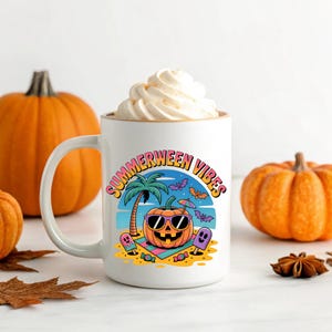 May include: White ceramic mug with the words "Summerween Vibes" and a cartoon pumpkin wearing sunglasses on a beach. The mug is filled with a white whipped topping. Two orange pumpkins are in the background.