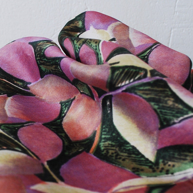 May include: Close-up of a pink and green floral fabric with a textured, abstract design. The fabric has a soft, flowing drape.