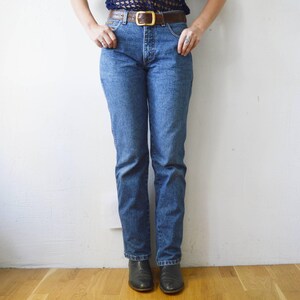 May include: A pair of blue denim jeans with a brown leather belt. The jeans have a straight leg and a high waist.