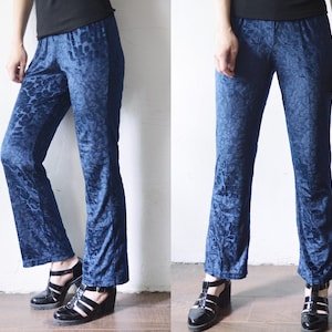 Puede incluir: Pantalón de terciopelo azul con estampado de leopardo. El pantalón tiene pierna ancha y se lleva con sandalias de tacón negras.