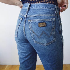 May include: A pair of blue denim jeans with a back pocket featuring a brown leather Wrangler label.
