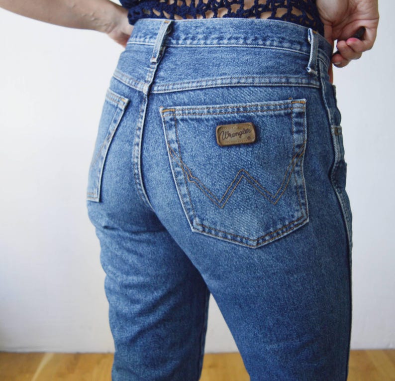 May include: A pair of blue denim jeans with a back pocket featuring a brown leather Wrangler label.