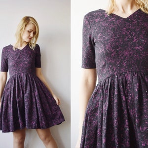 May include: A black and purple short-sleeved dress with a v-neck and a fit and flare silhouette. The dress has a small-scale floral print.