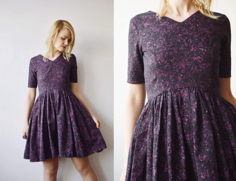 May include: A black and purple short-sleeved dress with a v-neck and a fit and flare silhouette. The dress has a small-scale floral print.