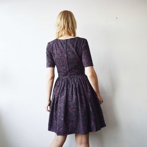 May include: A black and purple floral print dress with a short sleeve and a full skirt.